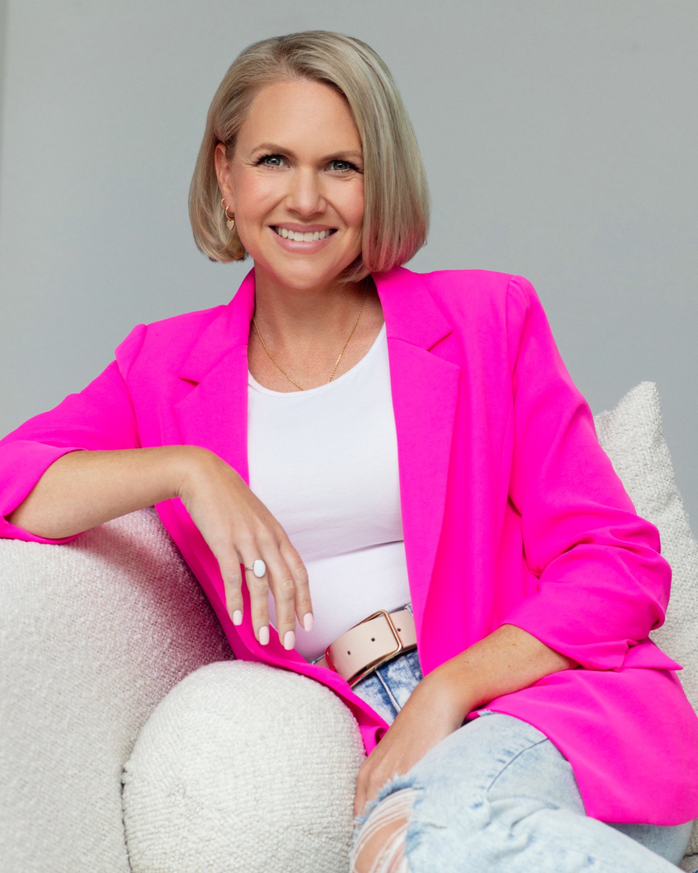 SarahBeth Bolin, LCSW, seated in a bright room in a hot pink blazer, smiling at the camera.